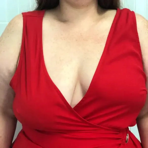 A close-up of a woman's chest in a red outfit is shown after using The Boob Tape, identified as Michelle J.